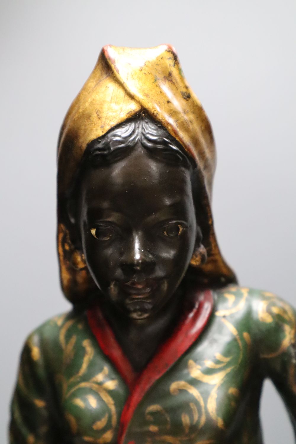 A pair of gilt and polychrome painted Nubian butlers, portrayed holding shell shaped trays